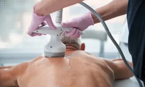 Cropped back-view of a shirtless man going through a procedure of ultrasonic cavitation at a salon